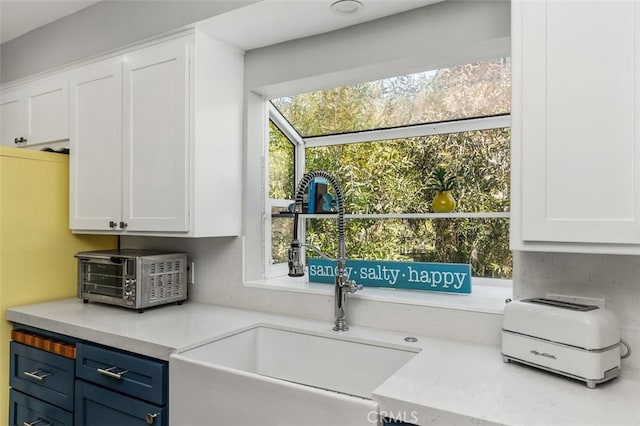 kitchen featuring white cabinets, a sink, light countertops, and blue cabinets