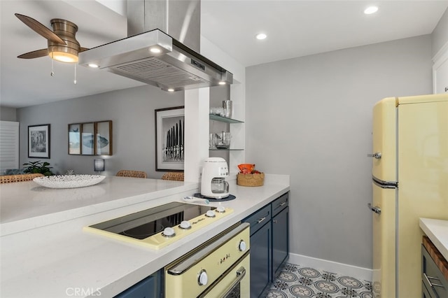 kitchen featuring blue cabinets, freestanding refrigerator, black electric stovetop, island exhaust hood, and light countertops