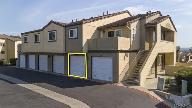 view of front of house with a garage, stucco siding, and a tile roof