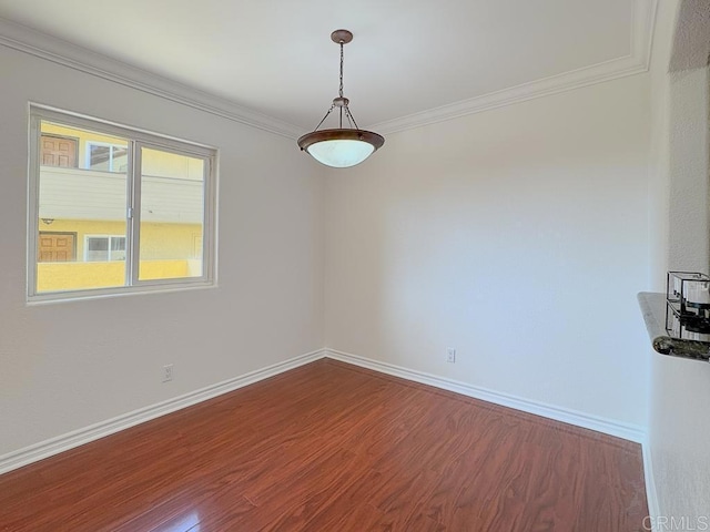 spare room with crown molding, baseboards, and wood finished floors