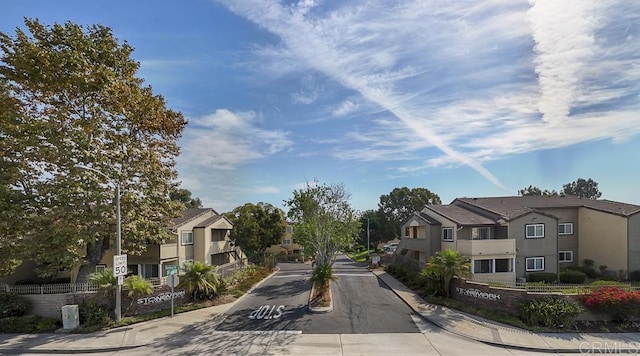 view of road featuring curbs, street lighting, a residential view, sidewalks, and traffic signs