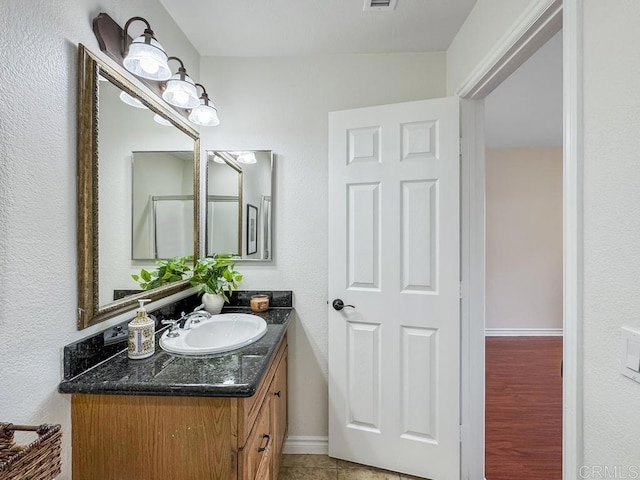 bathroom with baseboards, visible vents, tile patterned floors, and vanity