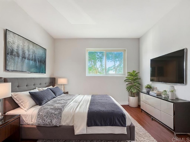 bedroom with a skylight, baseboards, and wood finished floors