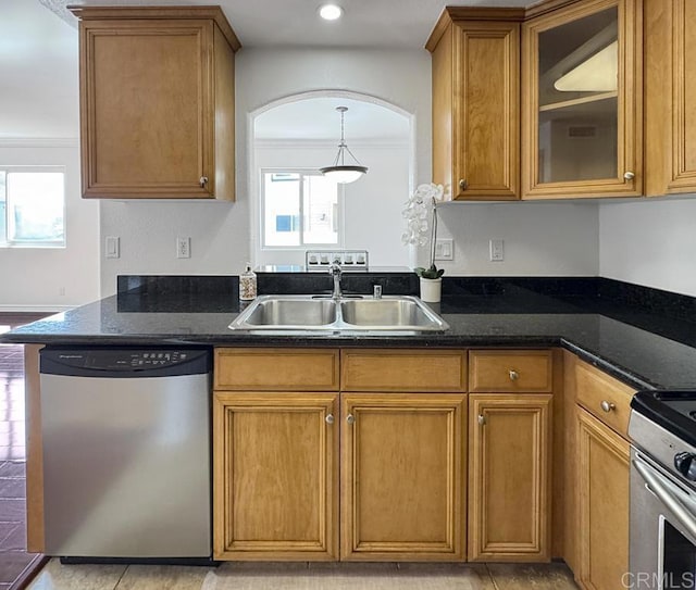 kitchen featuring plenty of natural light, appliances with stainless steel finishes, brown cabinets, a sink, and ornamental molding
