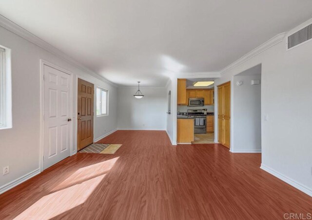 unfurnished living room with baseboards, visible vents, ornamental molding, and wood finished floors