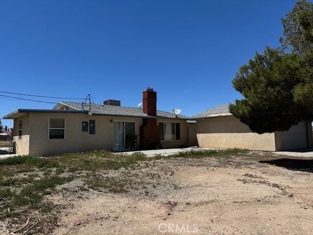 back of property featuring a chimney and stucco siding