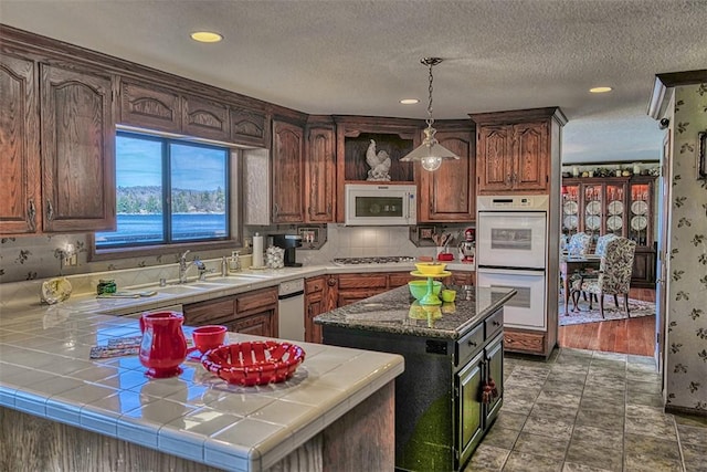 27990 Peninsula Dr N, Lake Arrowhead, CA 92352 - kitchen with pendant lighting, white appliances, a sink, tile counters, and backsplash