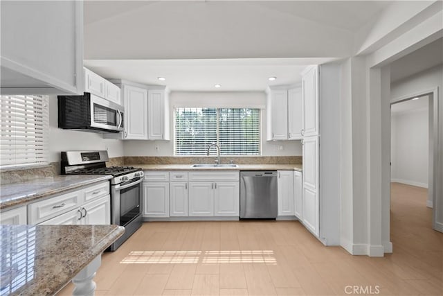 5025 Noble Ave, Sherman Oaks, CA 91403 - kitchen with appliances with stainless steel finishes, a sink, white cabinetry, light stone counters, and lofted ceiling