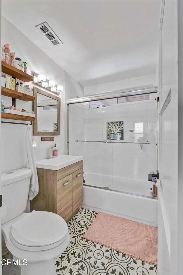 bathroom featuring visible vents, toilet, enclosed tub / shower combo, vanity, and tile patterned floors