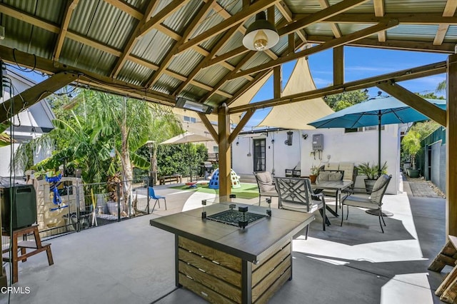 view of patio featuring outdoor dining space, a gazebo, fence, and an outdoor fire pit