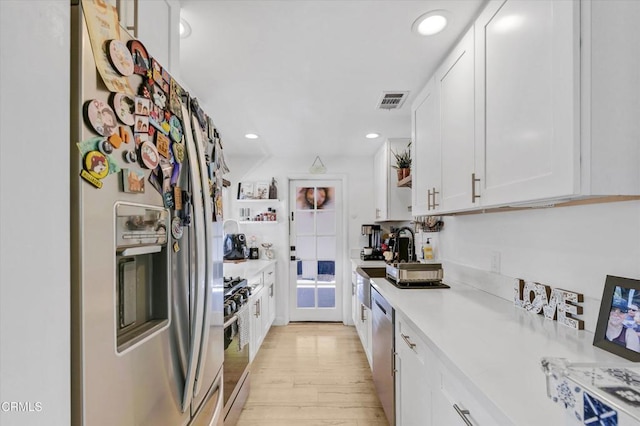 kitchen featuring light countertops, white cabinetry, light wood-style floors, visible vents, and appliances with stainless steel finishes