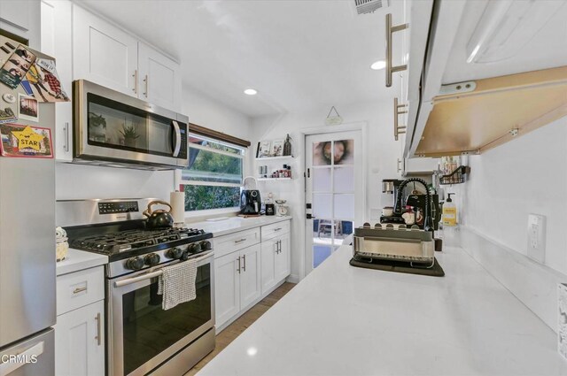 kitchen featuring white cabinetry, visible vents, appliances with stainless steel finishes, wood finished floors, and light countertops
