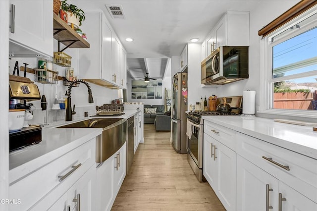 kitchen featuring light wood-style flooring, light countertops, a sink, and appliances with stainless steel finishes