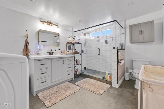 bathroom featuring toilet, washer / dryer, vanity, and a stall shower