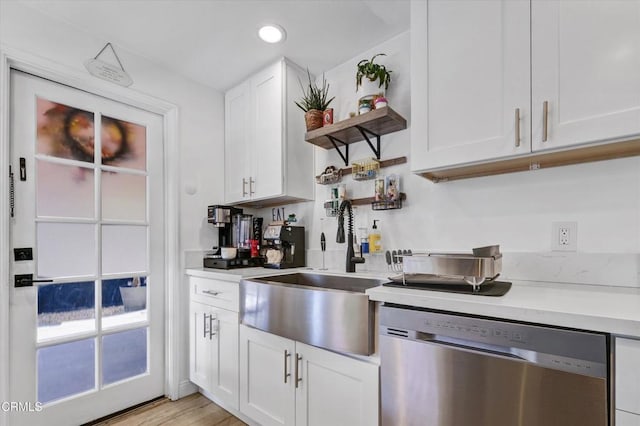 kitchen featuring light countertops, open shelves, white cabinets, stainless steel dishwasher, and a sink