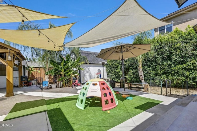 view of jungle gym with a patio area and fence