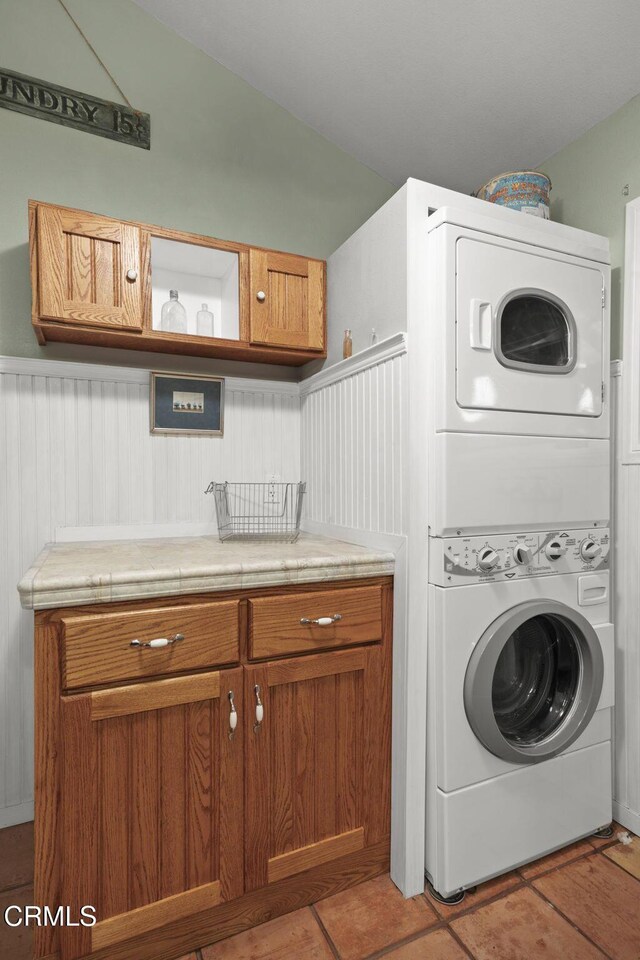 308 Topa Topa Dr, Ojai, CA 93023 - laundry room featuring stacked washer / drying machine, cabinet space, wainscoting, and light tile patterned flooring