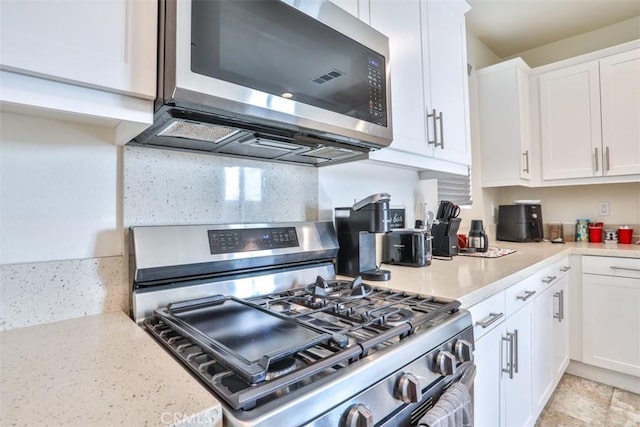kitchen with white cabinets, appliances with stainless steel finishes, and light stone countertops