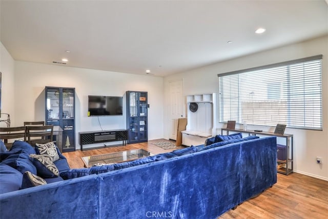living room with recessed lighting, visible vents, baseboards, and wood finished floors