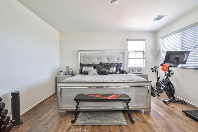 bedroom with visible vents, baseboards, and wood finished floors