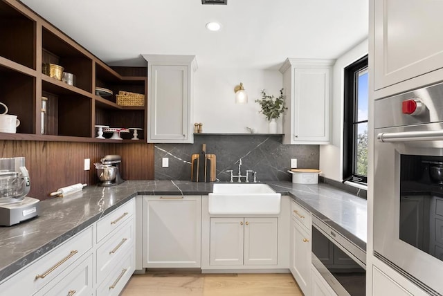 kitchen with white cabinets, open shelves, a sink, stainless steel appliances, and backsplash