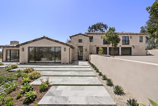 rear view of property with a fenced front yard, a garage, and stucco siding