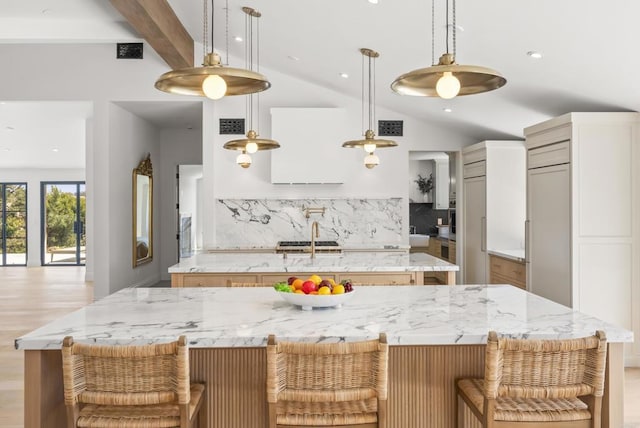 kitchen featuring light stone counters, vaulted ceiling with beams, visible vents, and a spacious island