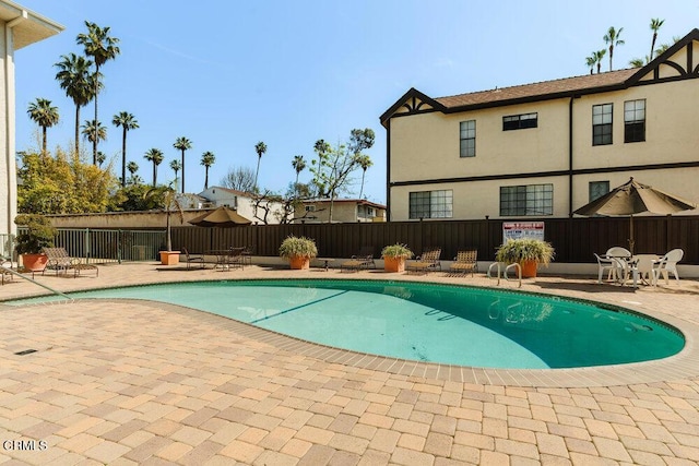 community pool with a patio area and fence