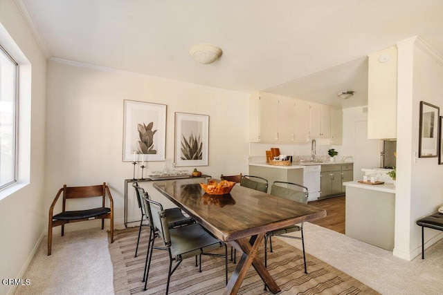 dining room featuring crown molding, baseboards, and light carpet