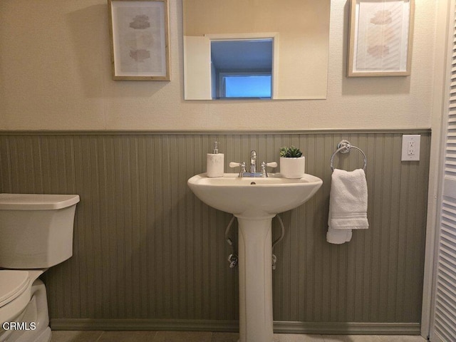 bathroom with toilet and a wainscoted wall