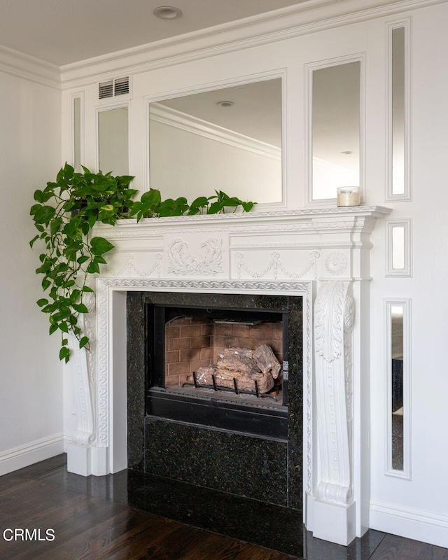 details with visible vents, baseboards, a high end fireplace, crown molding, and wood finished floors