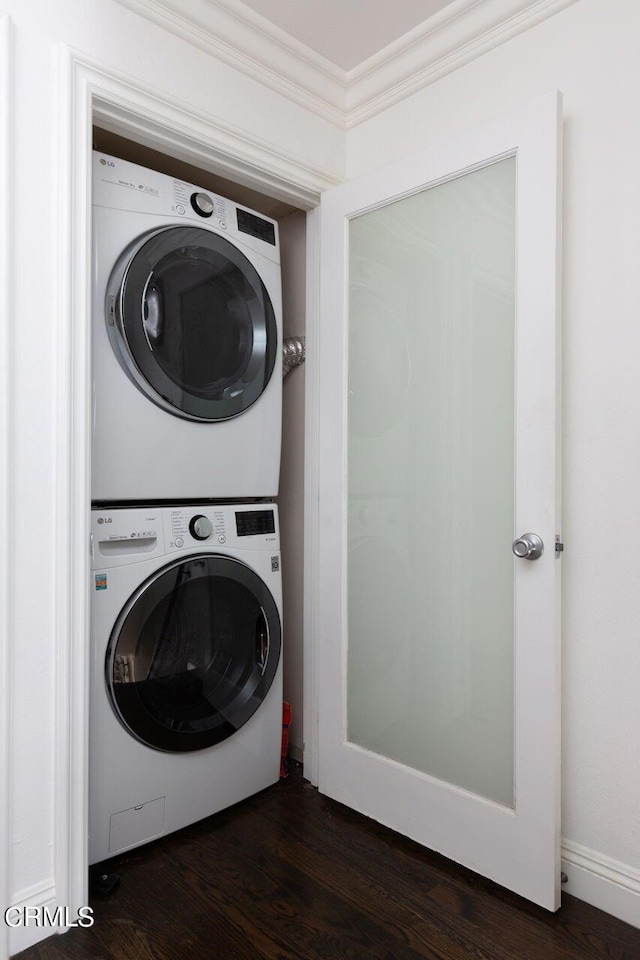 laundry area with dark wood-style floors, stacked washer and dryer, ornamental molding, and laundry area