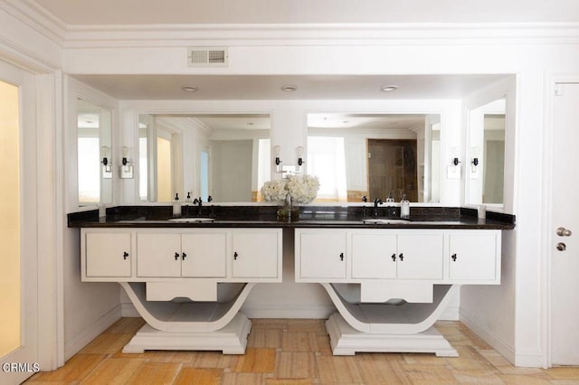full bathroom featuring a sink, visible vents, baseboards, and ornamental molding
