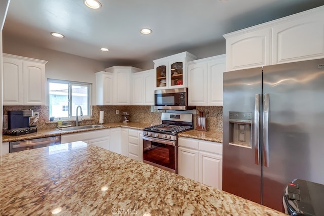 kitchen with a sink, backsplash, light stone countertops, and stainless steel appliances