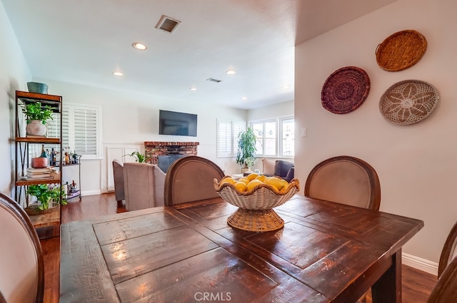 dining area with a fireplace, recessed lighting, visible vents, and wood finished floors