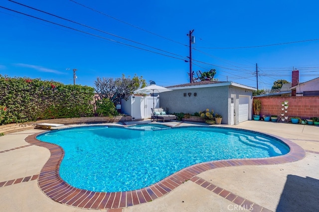 view of pool featuring a diving board, a patio area, an outbuilding, a pool with connected hot tub, and fence