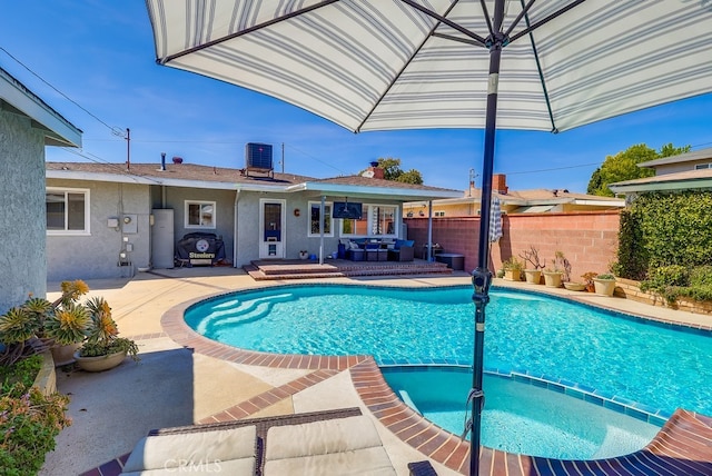 view of swimming pool with a patio area, a pool with connected hot tub, fence, and central AC