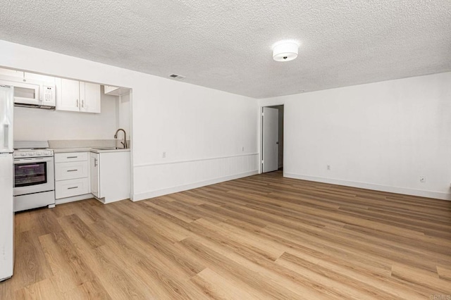 kitchen featuring white appliances, light wood-type flooring, white cabinetry, light countertops, and a sink