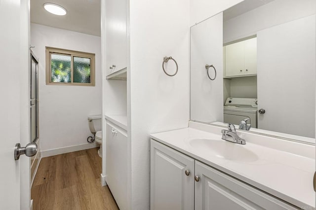full bath featuring washer / clothes dryer, baseboards, toilet, vanity, and wood finished floors