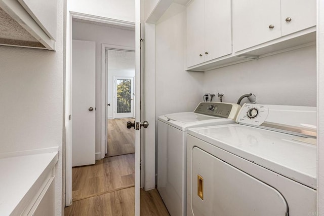 washroom with light wood-style floors, washing machine and dryer, and cabinet space