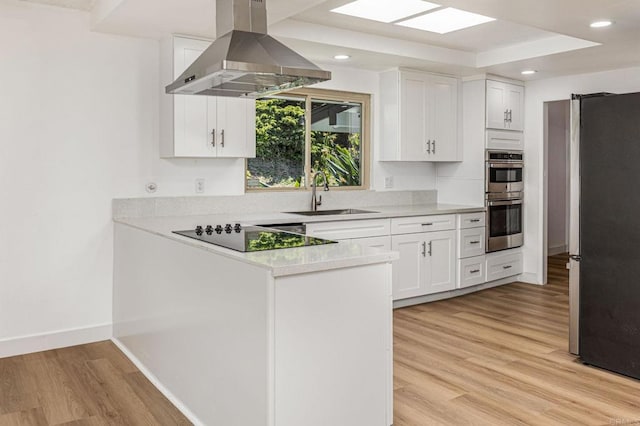 kitchen with a sink, appliances with stainless steel finishes, white cabinetry, island range hood, and light wood-style flooring