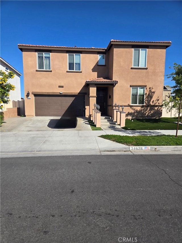 view of front of home with concrete driveway, an attached garage, a tiled roof, and stucco siding