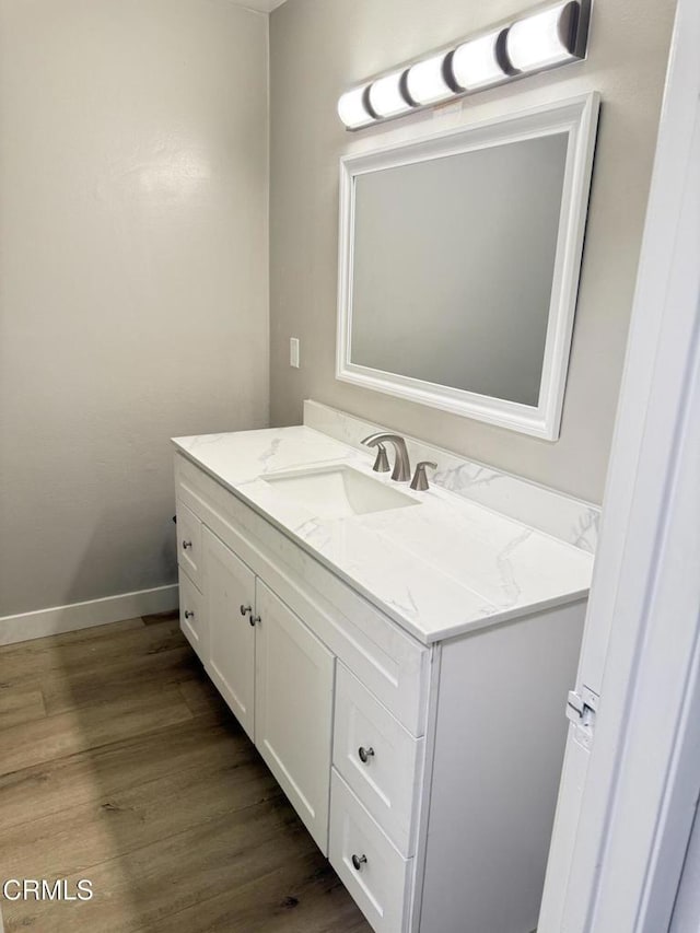 bathroom with wood finished floors, vanity, and baseboards