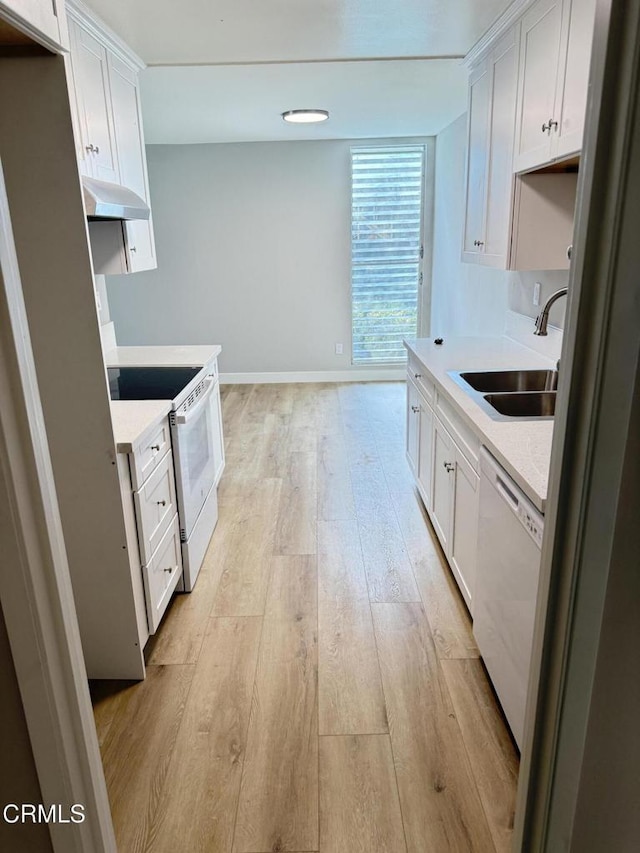 kitchen featuring a sink, light countertops, white appliances, under cabinet range hood, and light wood finished floors