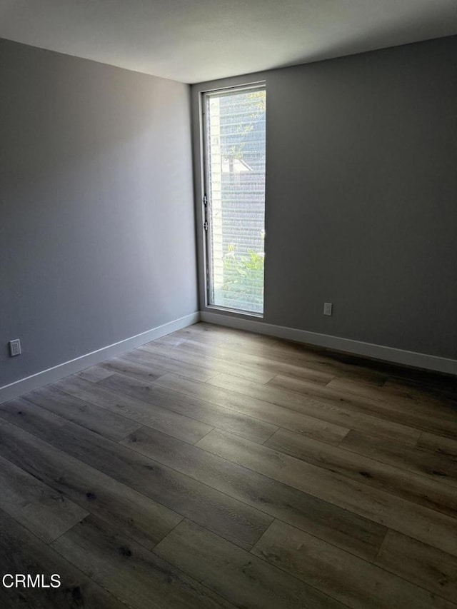 spare room with dark wood-type flooring and baseboards