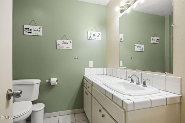 half bath with toilet, vanity, baseboards, and tile patterned flooring