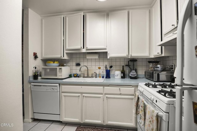 kitchen featuring a sink, light countertops, tasteful backsplash, and white appliances