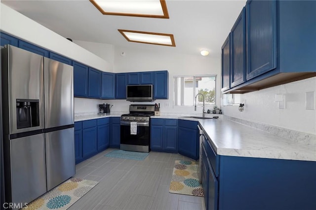 40824 Cobblestone Ct, Palmdale, CA 93551 - kitchen featuring appliances with stainless steel finishes, blue cabinets, vaulted ceiling, a sink, and light countertops