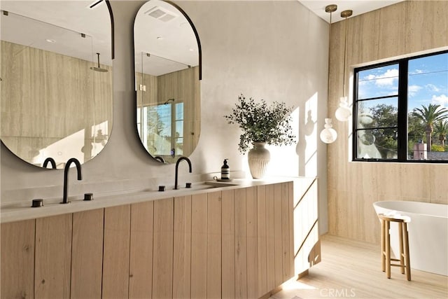 bathroom with visible vents, a freestanding bath, wood finished floors, a shower, and a sink