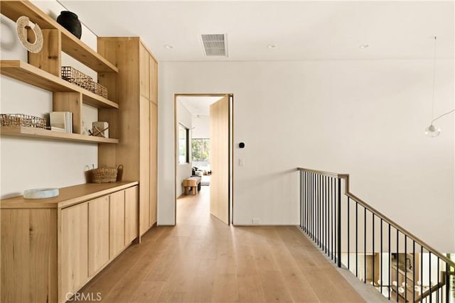 hall featuring light wood-style flooring and visible vents